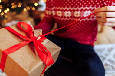 young man is holding a Christmas present with a red ribbon. Close-up, Gift opening