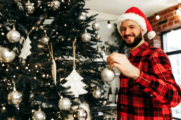 Young Happy Man Santa Claus Hat Decorates Christmas Tree Toys — ストック写真