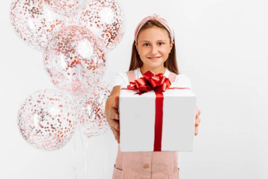 Sevimli küçük bir çocuğun portresi, balonlu ve hediyeli doğum günü kızı, izole edilmiş beyaz bir arka plan, tatil kavramı, doğum günü