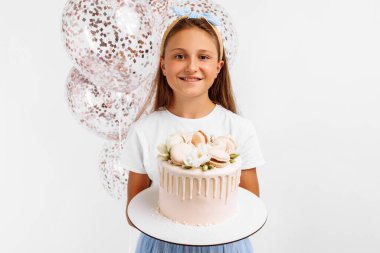 Güzel mutlu küçük kız elinde kocaman bir doğum günü pastası, balonlarla doğum günü kutlaması, izole edilmiş beyaz arka plan.