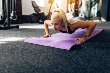 Spor salonunda, spor minderinde şınav çeken ince bir kadın. Spor, sağlıklı yaşam tarzı