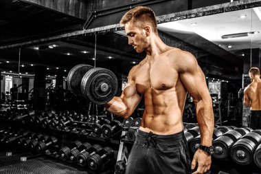 Modern bir spor salonunda halterle ağırlık kaldıran çekici kaslı vücut geliştirici.