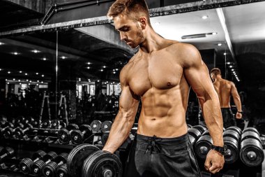 Modern bir spor salonunda halterle ağırlık kaldıran çekici kaslı vücut geliştirici.