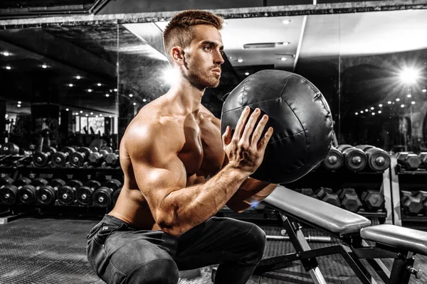 Fotografia do Stock: Entrenando en el gimnasio. Hombre con grandes músculos  levantando peso mientras entrena en el gimnasio. Ponerse en forma.