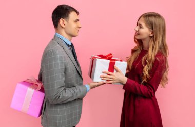 Sevgililer Günü konsepti. Sevgi dolu bir çift sevgililer gününü kutlar ve birbirlerine pembe arka planda hediyeler verir.