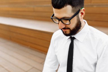 Gözlüklü, beyaz gömlekli, kravatlı genç bir iş adamı.