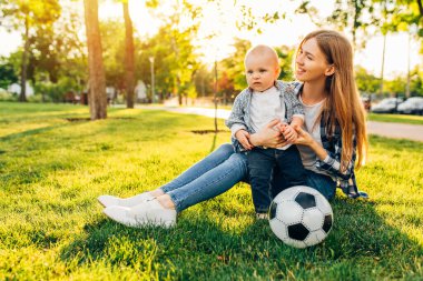 Mutlu aile, anne ve küçük oğlu parkta futbol oynuyorlar. Aile eğlencesi.