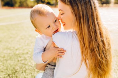 Mutlu anne, güneşli bir yaz gününde parkta bebeğini öper ve ona sarılır. Anneler gününde.