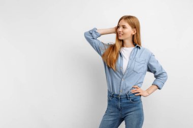 Güzel, mutlu, genç bir kadın beyaz arka planda poz veriyor ve kameraya bakıyor.