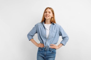 Kollarını kavuşturup beyaz arka planda izole edilmiş kameraya bakan gülümseyen genç bir kadının portresi.