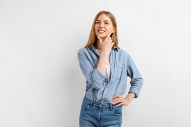 Güzel, mutlu, genç bir kadın beyaz arka planda poz veriyor ve kameraya bakıyor.