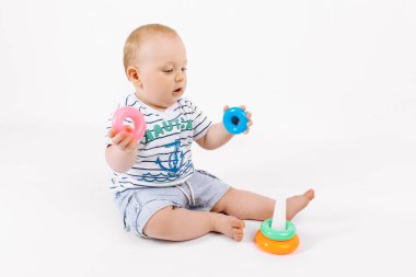 İzole edilmiş beyaz bir arka planda çocukların çok renkli piramitleriyle oynayan küçük şirin çocuk, erken gelişim, anaokuluna hazırlanıyor.