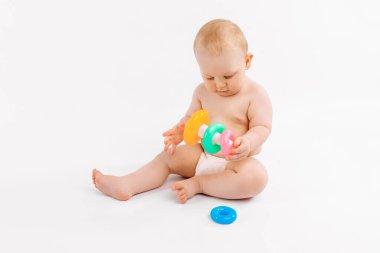 Çocuk bezli küçük bir bebek, izole edilmiş beyaz bir arka planda çok renkli piramit geliştiriyor, erken gelişim, anaokuluna hazırlanıyor.