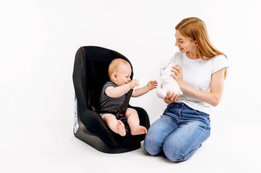 Dükkanda bebekli bir anne izole edilmiş beyaz bir arka planda araba koltuğu alır.