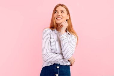 Genç bir kadın, pembe arka plana bakarak bir fikir edinmeyi düşünüyor.