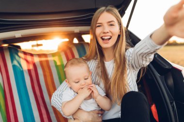 Tatil, seyahat, yaz tatiline çıkmaya hazır aile, arabanın bagajında küçük bir çocuğu olan mutlu bir anne.
