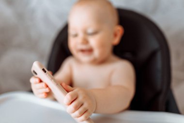 Cep telefonuyla beslenme sandalyesinde oturan mutlu çocuk portresini kapat