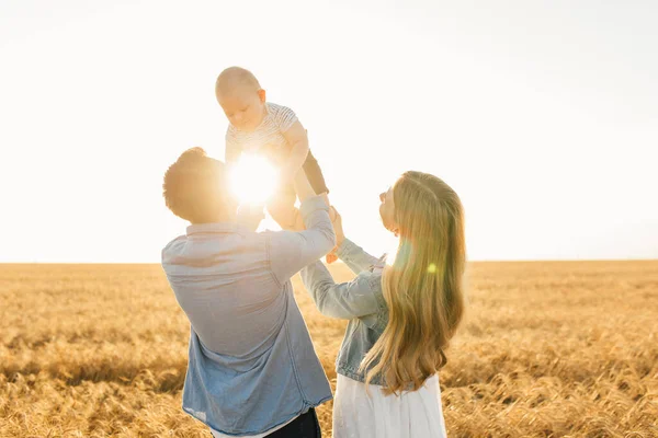 Happy family on a summer walk, Mother, father and son walk in the wheat field and enjoy the beautiful nature