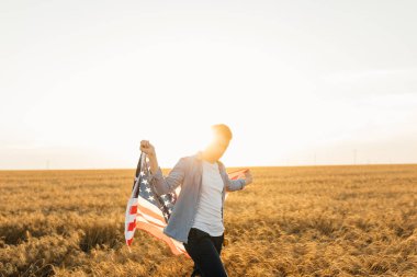 Amerika 'nın mutlu genç adamı. Gün batımında Amerika bayrağı sahada.