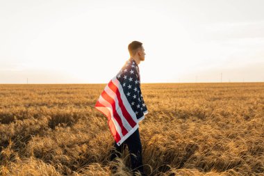 Amerika 'nın mutlu genç adamı. Gün batımında Amerika bayrağı sahada.