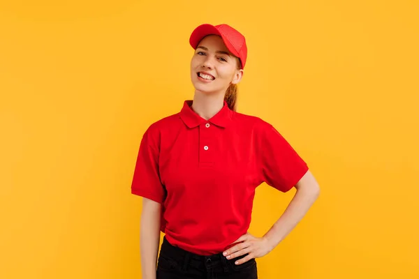 身穿红色制服的年轻女信使面带微笑 摆出黄色工作室背景 交付理念 — 图库照片