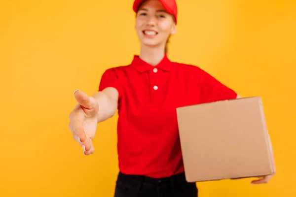 Dostawa Czerwonym Mundurze Paczką Kartonową Kobieta Pracująca Jako Kurier Żółtym — Zdjęcie stockowe