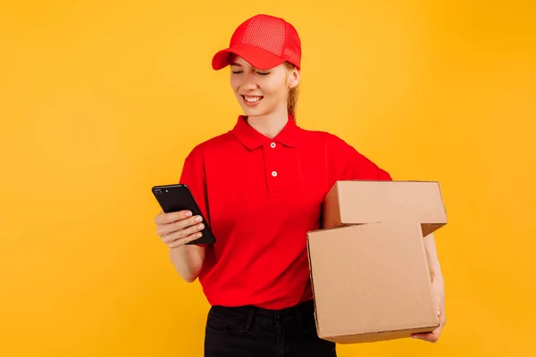 Kırmızı Şapkalı Tişörtlü Teslimatçı Kadın Sarı Arka Planda Cep Telefonu — Stok fotoğraf
