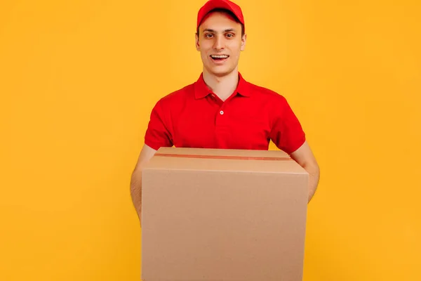 快乐而兴奋的男性信使 身穿红色T恤 头戴黄色背景的礼帽 快速送货 购物理念 — 图库照片