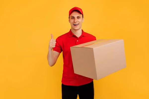 快乐而兴奋的男性信使 身穿红色T恤 头戴黄色背景的礼帽 快速送货 购物理念 — 图库照片