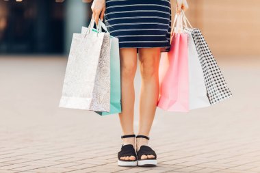 Alışverişe gidelim. Kadının elinde alışveriş merkezinin arka planında renkli alışveriş torbaları var. Moda.