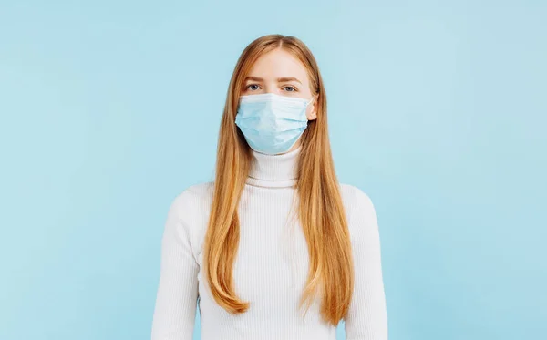 若い女性が隔離された青い背景で医療マスクの中で社会的距離を保つ写真 — ストック写真