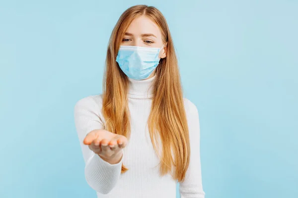 青い背景に隔離された空間をコピーするために指で指す医療用マスクの幸せな若い女性の肖像画 — ストック写真