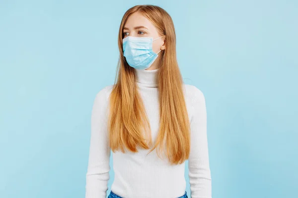 若い女性が隔離された青い背景で医療マスクの中で社会的距離を保つ写真 — ストック写真