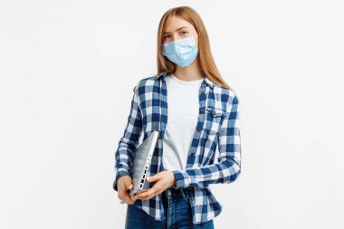 Beyaz bilgisayarla izole edilmiş, koruyucu maskeli, çekici, mutlu genç bir kadının portresi.