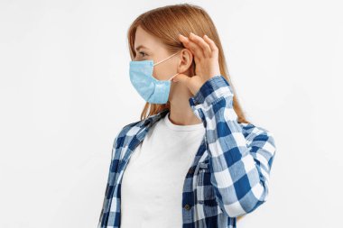 Virüslerden korunan koruyucu maske takan genç ve güzel bir kadın. Kulaktan kulağa yayılan dedikoduları ve dedikoduları dinliyor.