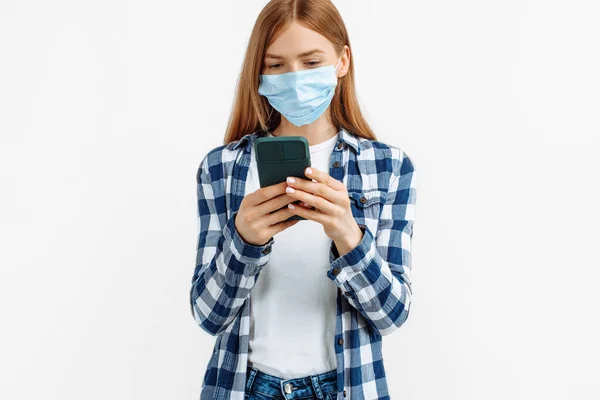 Giovane Donna Maschera Medica Utilizza Telefono Cellulare Uno Sfondo Bianco — Foto Stock