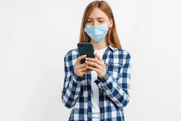 Mulher Jovem Uma Máscara Médica Usa Telefone Celular Fundo Branco — Fotografia de Stock