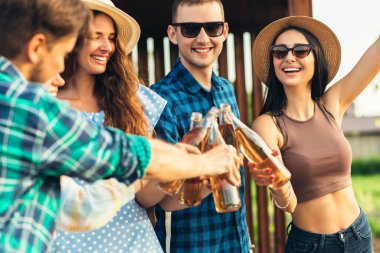 Bir grup genç arkadaş dışarıda bir partide eğleniyor, soğuk içecekler içiyor, barbekü yapıyor ve ızgara sebze yapıyor, sıcak yaz günlerinin tadını çıkarıyorlar.,