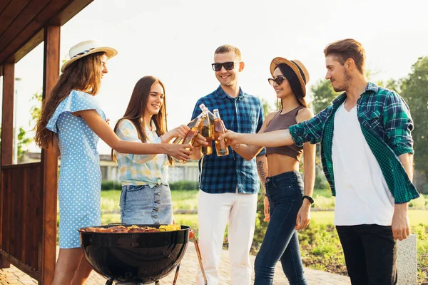 自然の中でバーベキューパーティーをしている若い幸せな友人のグループ 友人は夏に屋外で肉を炒め チャットし レモネードを飲む — ストック写真