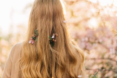 Hoş bir genç kadın, narin bir elbise içinde, ağaçların renkli pembe çiçeklerinin yanında duruyor, romantik kadınlar.