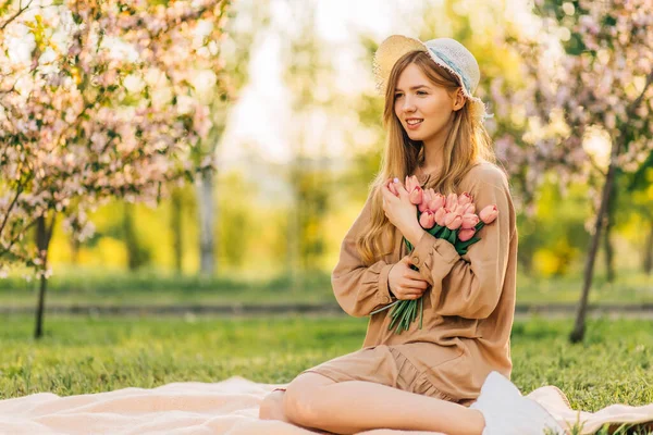 아름다운 미소짓는 여자가 꽃다발을 공원의 잔디밭에 여름날 자연을 만끽하는 — 스톡 사진