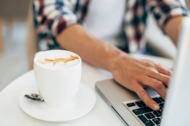 Çalışan, tahta masada dizüstü bilgisayar kullanan, klavyede yazan, evden çalışan ya da interneti online alışveriş ve sosyal ağlar için kullanan bir adam.