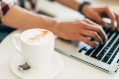 Çalışan, tahta masada dizüstü bilgisayar kullanan, klavyede yazan, evden çalışan ya da interneti online alışveriş ve sosyal ağlar için kullanan bir adam.