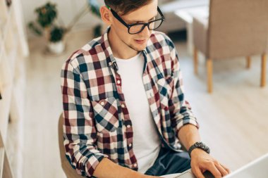 Çekici erkek işçi kafeteryada bilgisayar kullanıyor, genç adam dizüstü bilgisayar kullanıyor.