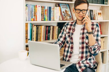 Gülümseyen, şık, gözlüklü genç bir erkek öğrenci, dizüstü bilgisayar kullanan ve cep telefonuyla konuşan başarılı bir adam, kütüphanede kitaplarla arka planda okuyan bir öğrenci.