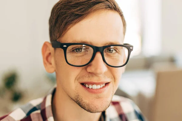 Portrait of a happy young man wearing glasses and casual plaid shirt, happy man smiling and looking at camera