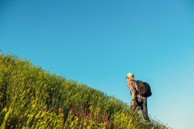 Genç bir turist, sırt çantalı bir adam, yürüyüşler, dağlarda yürüyüş, sırt çantalı bir turist, dağlara bakıyor. Gülümseyen adam, aktif sağlıklı yaşam tarzı, macera yolculuğu, tatil