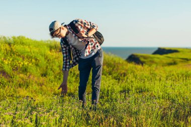 Sırt çantalı gülümseyen genç adam, tek başına yürürken panoramasını seyrediyor, turist sırt çantasıyla güzel doğaya bakıyor, gülümseyen adam.