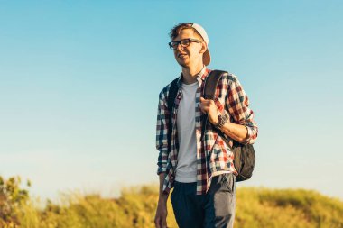 Genç bir adam, sırt çantalı bir turist, araştırma gezisinde, yan manzaralı gezgin portresi, yan tarafa bakıyor.