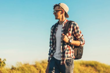 Genç bir adam, sırt çantalı bir turist, araştırma gezisinde, yan manzaralı gezgin portresi, yan tarafa bakıyor.